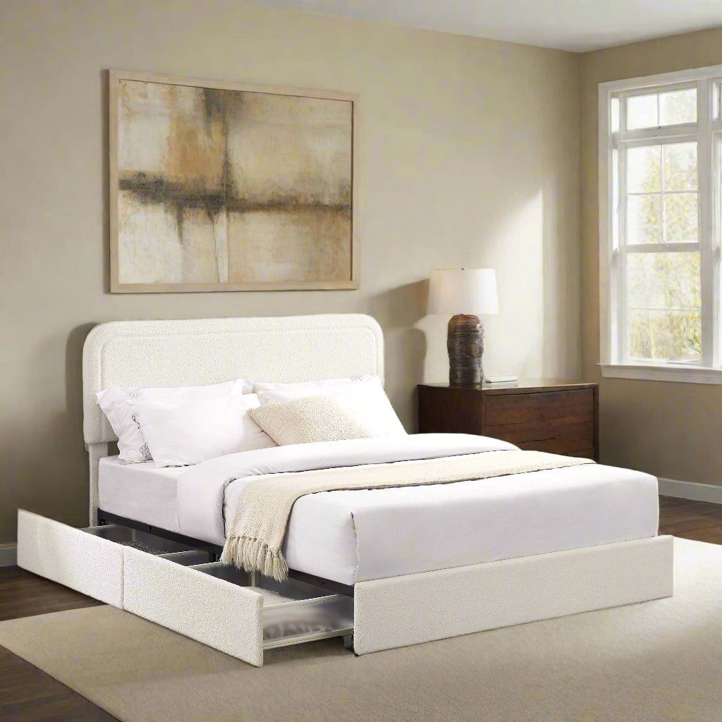 A queen-sized ivory boucle upholstered platform bed with a storage system that includes two drawers, placed in a room with a white padded headboard and a lamp on the side table.