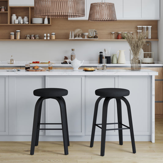 Two black bar stools in front of a kitchen counter with white cabinets and wooden shelves.