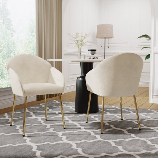 Two modern side chairs with beige upholstery and gold legs, set in a room with a black round table and a white pendant lamp.