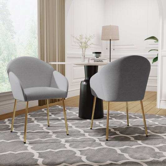 Two modern side chairs with gray upholstery and gold metal legs, positioned in a room with a contemporary interior design.